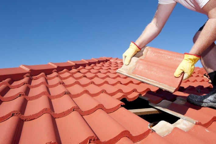 man repairing red roof