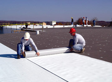 Two Austin commercial roofing professionals working on a large roof