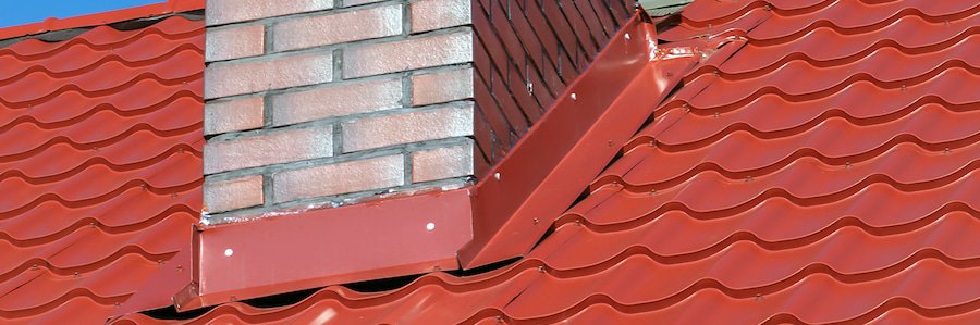 Roof flashing around a brick chimney on a metal roof.