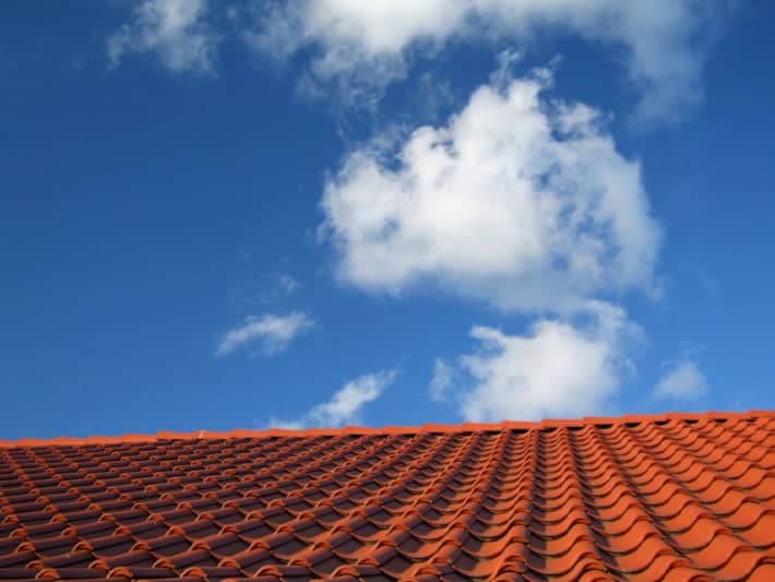 blue sky with cloud above red tile roof